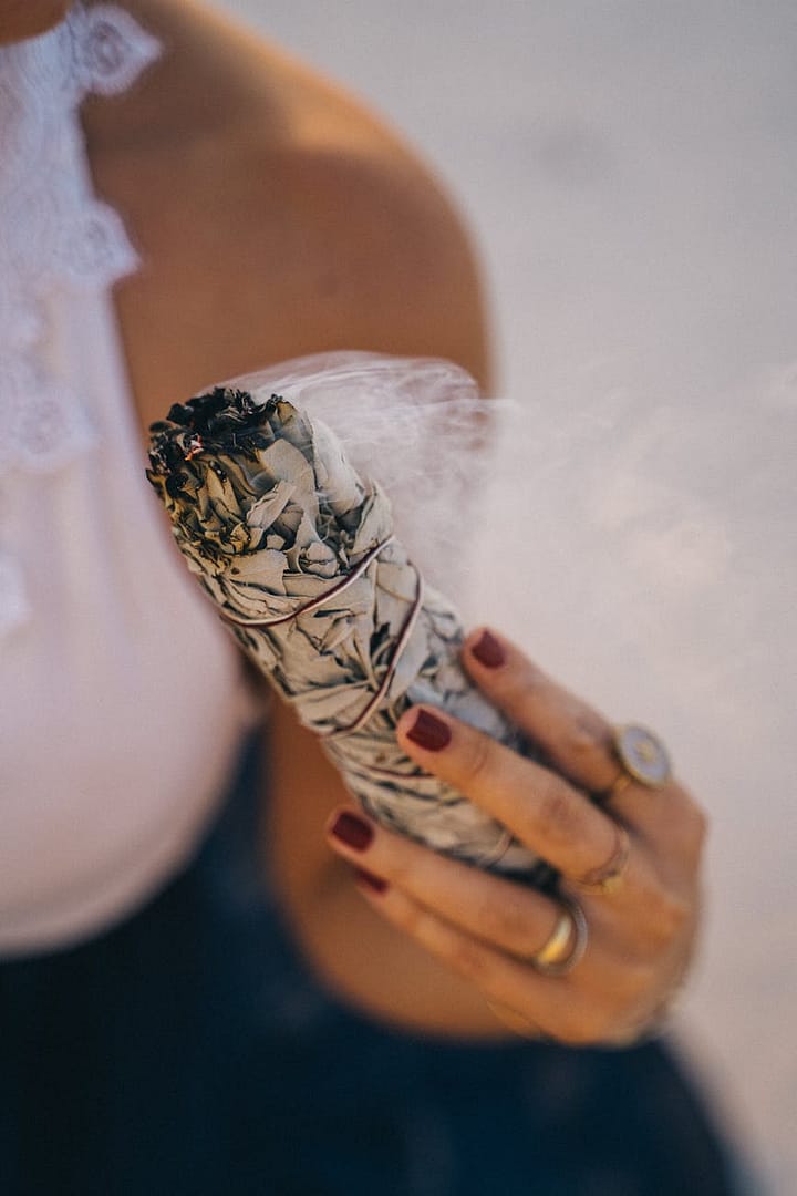 woman holding a burning white sage